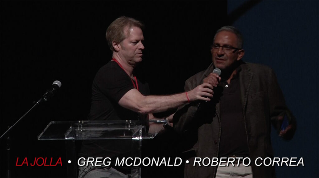 Director Greg McDonald helps Rob erto with microphone at La Jolla Fashion Film Festival